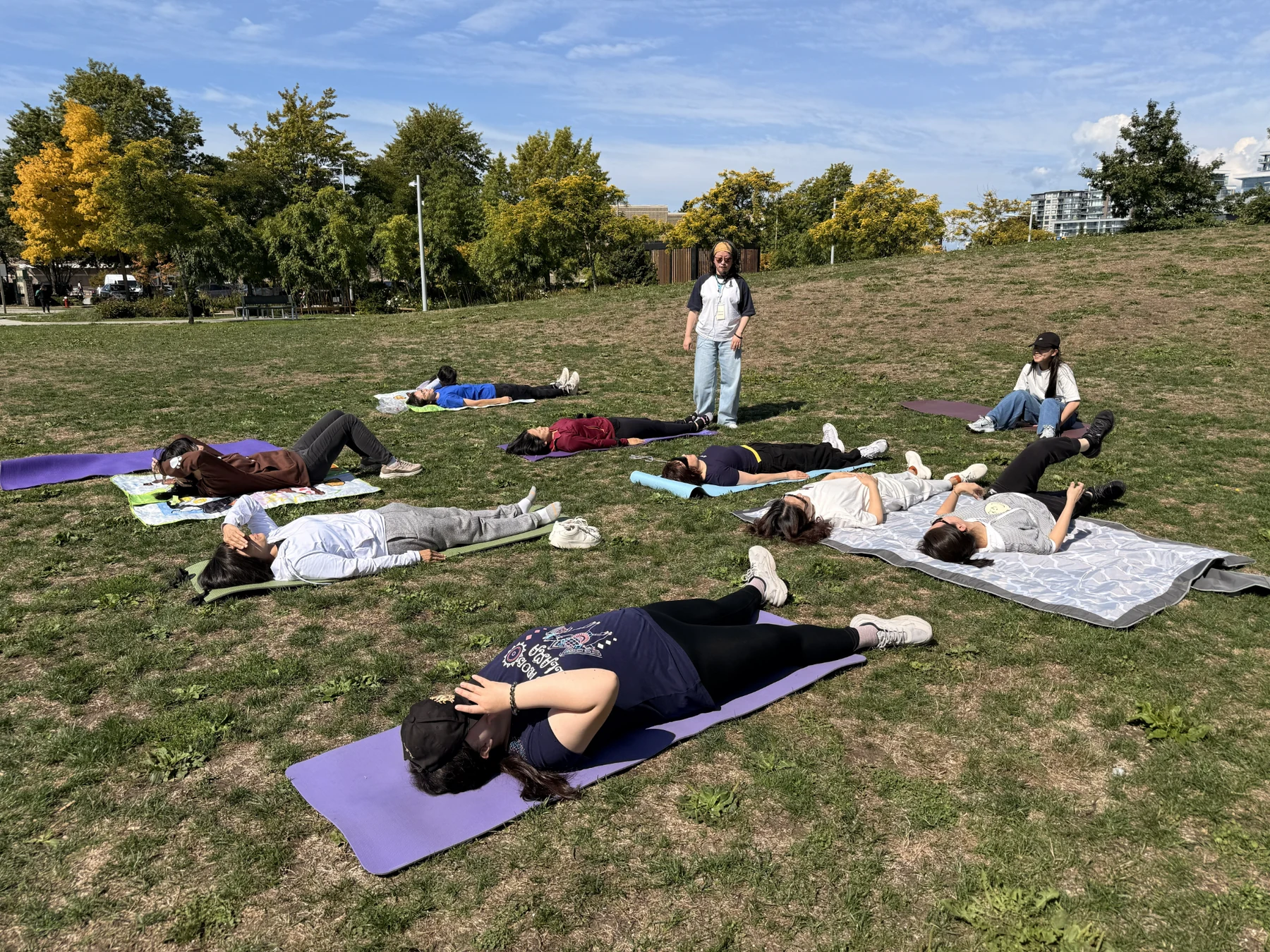 Participants lying on mats and blankets while learning a gentle qigong exercise outdoors.