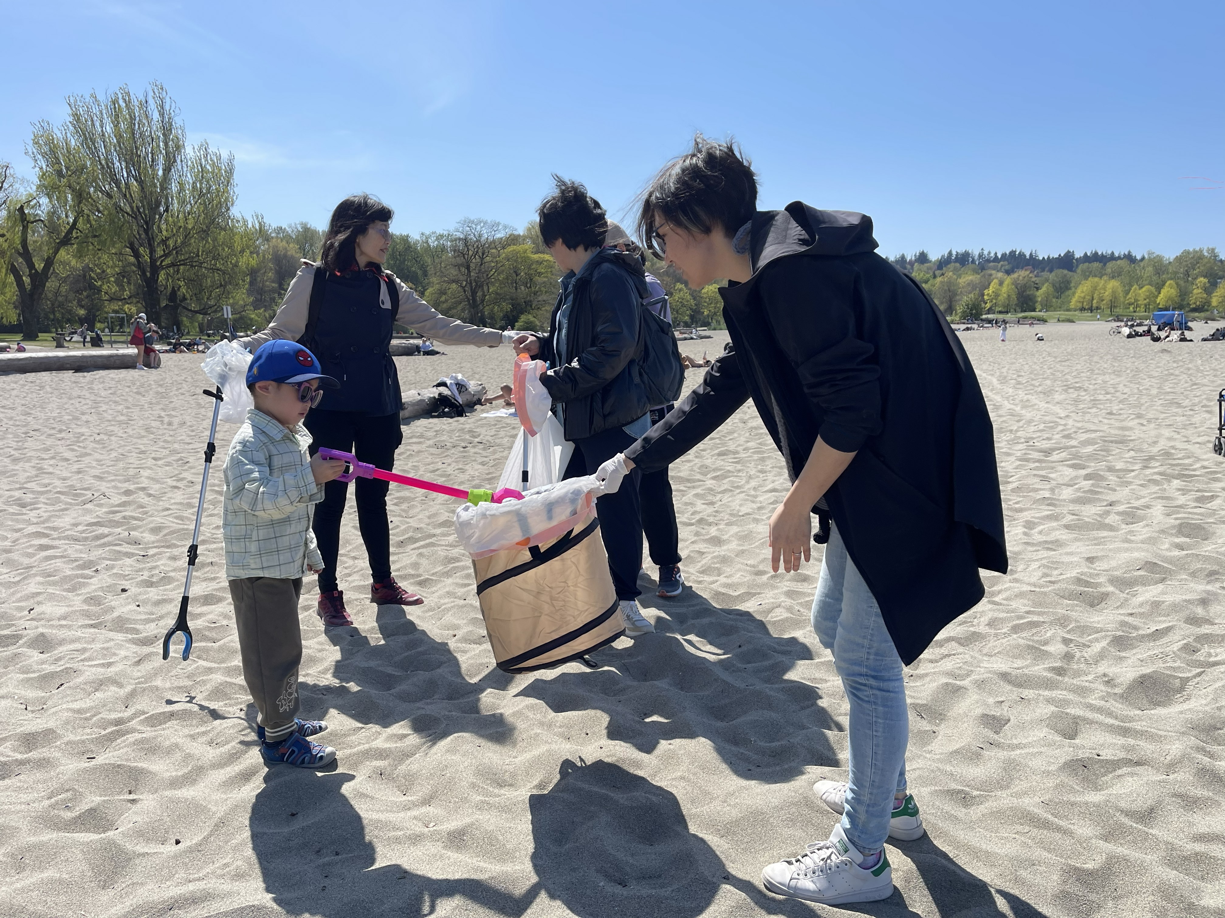 Volunteers cleaning a beach together on a bright day.